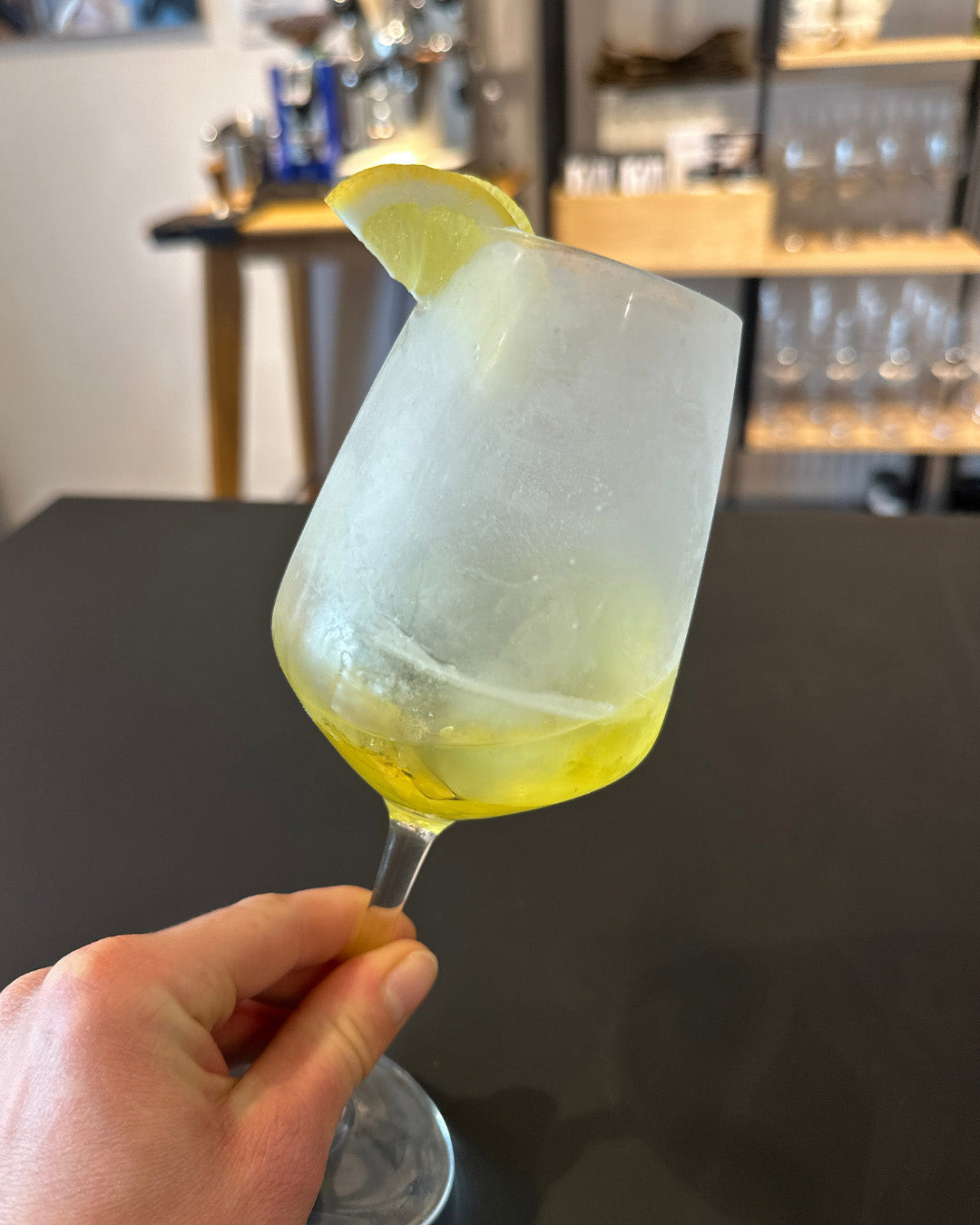 Aperitif in Weinglas mit Zitronenscheibe.