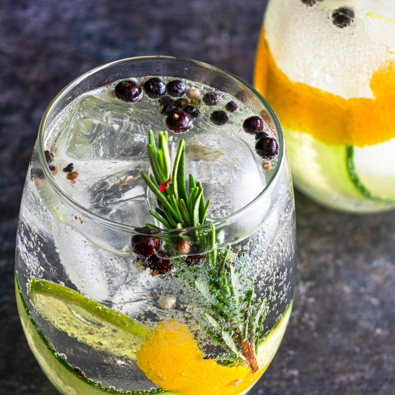 Gin Tonic mit Rosmarin Wacholderbeeren und Orangenscheiben auf Eis